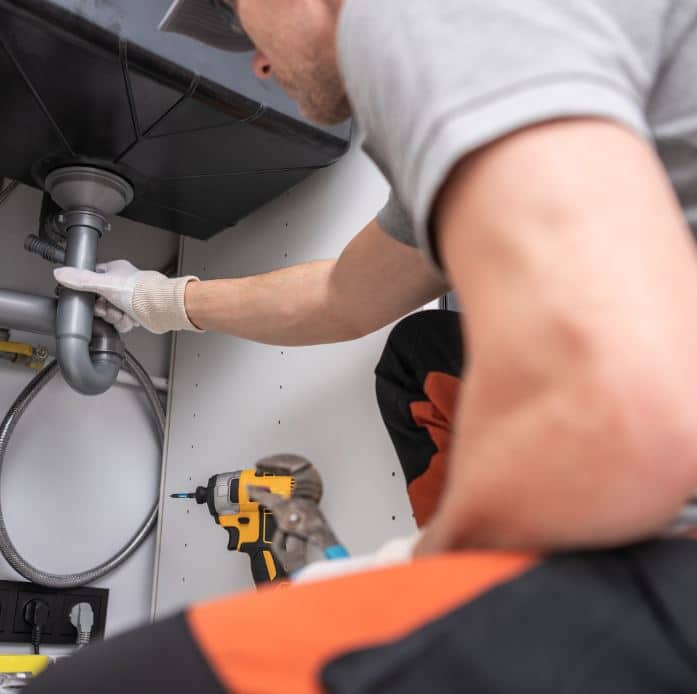 drain repair services man holding hose at top of water heater