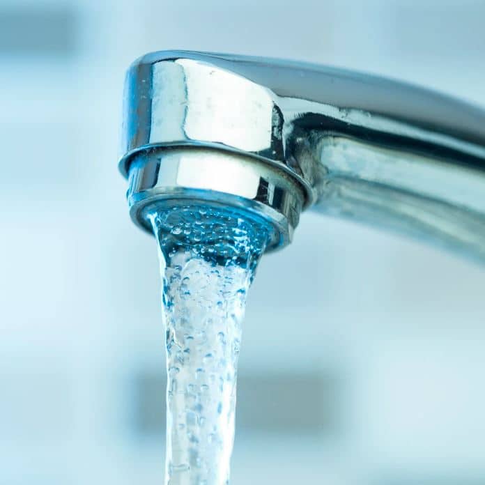 man holding hose at top of water heater
