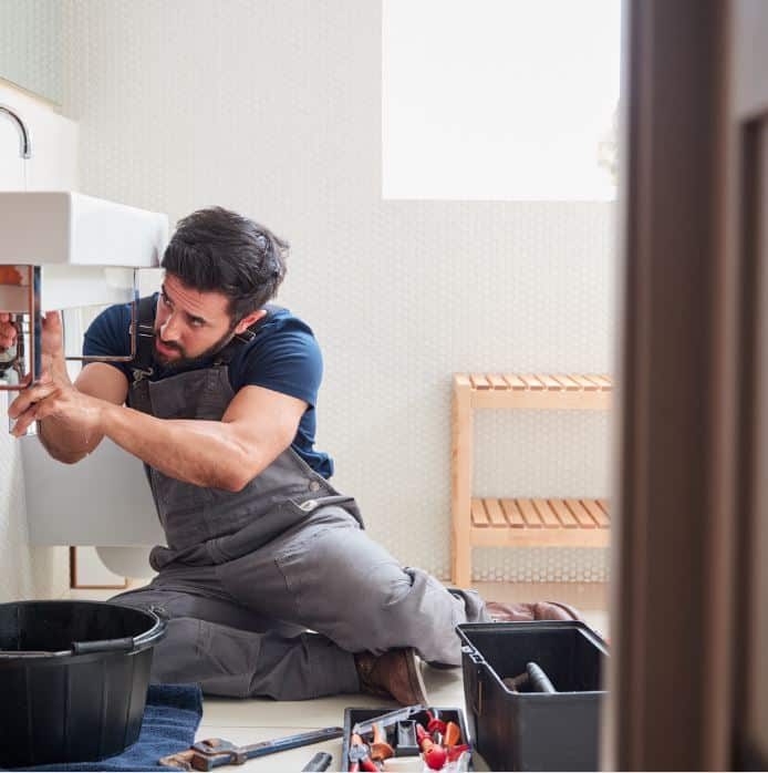 sink man holding hose at top of water heater