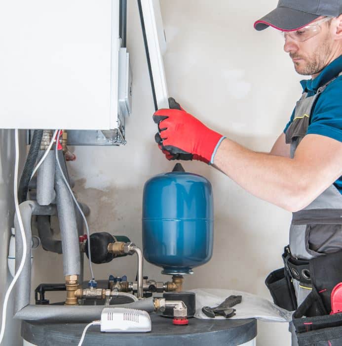 water heater services man holding hose at top of water heater