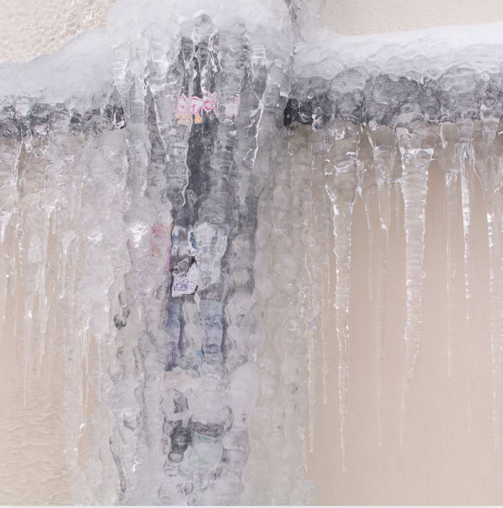 frozen pipe man holding hose at top of water heater